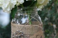a rustic wedding centerpiece of a jar wrapped with burlap, twine and with a vintage key, white hydrangeas for a rustic wedding