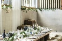 a rustic wedding reception space with a table made using hay and a planked tabletop, hay wrapped with burlap that work as stools