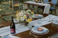 a simple and pretty backyard wedding tablescape with white and blue linens, bold blooms and gold cutlery is all cool