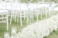 a spring wedding aisle with baby’s breath liners and arrangements, with floating candles in glasses is a timeless idea that will give a slight vintage feel
