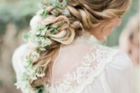 a twisted and curled braid with a texture on top and greenery and whiet blooms in the braid