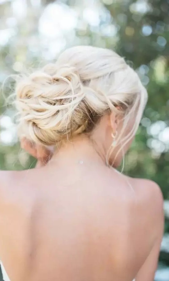 a twisted low bun with some locks down, with locks framing the face is a gorgeous idea for a chic and elegant look not only at a beach wedding