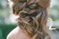 a wavy and braided half updo with a bump is a stylish and chic idea for a wedding