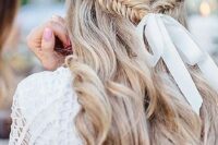 a wavy half updo with a fishtail braid secured with a white ribbon and a bow is a very relaxed boho idea