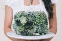 a wedding cake completely covered with succulents and air plants is a cool idea for a modern boho wedding