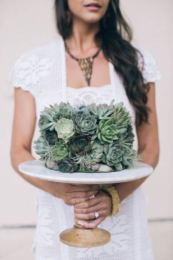 a wedding cake completely covered with succulents and air plants is a cool idea for a modern boho wedding
