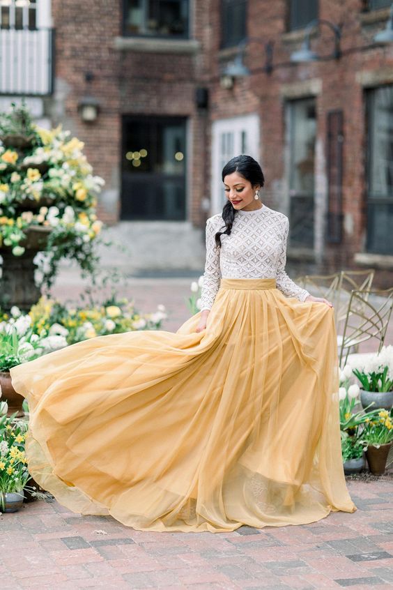 a white crochet lace top with a high neckline and long sleeves, a yellow pleated skirt for a bright and fun look