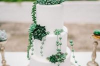 a white sleek wedding cake with real and sugar succulents and cacti is chic and stylish