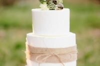 a white wedding cake accented with burlap and twine, with white blooms and seeds pods is a pretty and catchy idea for a rustic wedding
