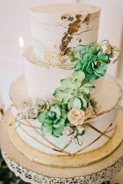 a white wedding cake with gold leaf and gold stripes, with sugar succulents, blooms and twigs is a lovely idea for many weddings with a glam touch