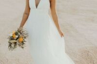 an A-line plain wedding dress with an illusion plunging neckline, thick straps and a layered skirt plus statement earrings