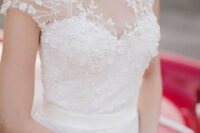 an adorable cap sleeve wedding dress with a beaded bodice, an illusion sweetheart neckline, floral appliques and a draped skirt