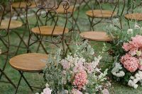 an exquisite spring wedding aisle with a vintage feel, done with greenery, pink, mauve and white blooms and vintage chairs