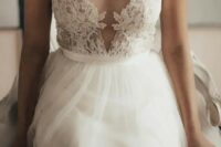 an illusion plunging neckline sleeveless wedding dress with a lace applique bodice and a tulle skirt