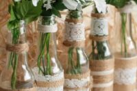 bottles wrapped with lace and twine, with baby’s breath and daisies are simple DIY wedding centerpiece you can make fast