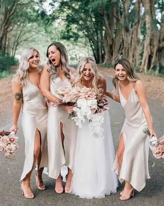 comfy and cool white slip midi bridesmaid dresses with front slits and V-necklines plus nude heels for a spring or summer wedding