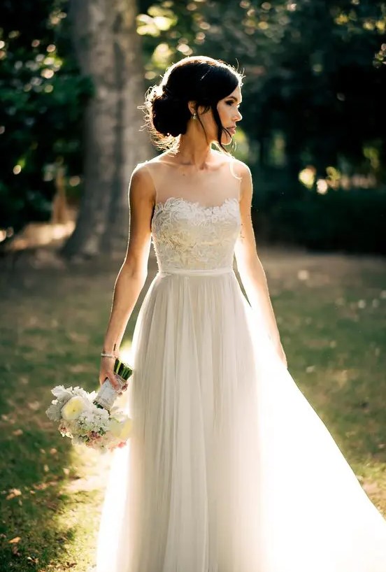 ethereal sleeveless wedding dress with a lace applique bodice, a faux sweetheart neckline and a layered skirt