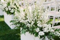 white chairs and white planters with greenery and white blooms make up a chic and stylish modern wedding aisle