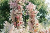 06 a fantastic and super lush wedding arch with pink, yellow and orange blooms and blooming branches plus pink baby’s breath all over