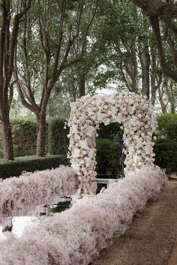 a fantastic lush white and blush wedding arch, an aisle covered with mirrors and lined up with blush baby's breath is a gorgeous idea for spring