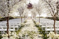 11 a jaw-dropping and breathtaking wedding ceremony space with blooming trees and white hydrangeas lining up the aisle and white petals on it