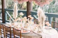 14 a beautiful and dreamy boho wedding tablescape with pink roses and pampas grass plus a pink baby’s breath installation over it