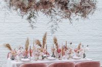 15 a rose-inspired wedding reception space with pampas grass, touches of pink and a pale greenery and blush floral and greenery installation over the table