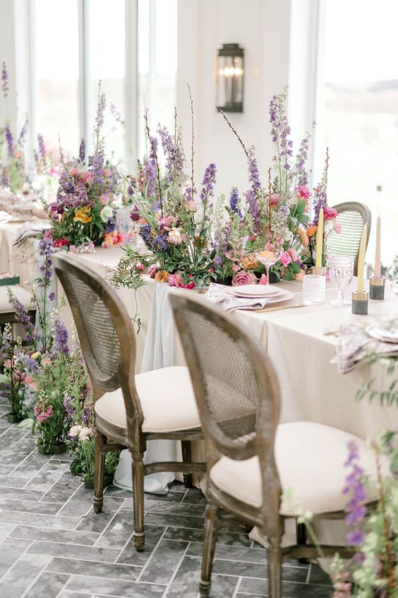 bright freeform florals placed on the reception tables and on the floor create a feeling of an indoor garden