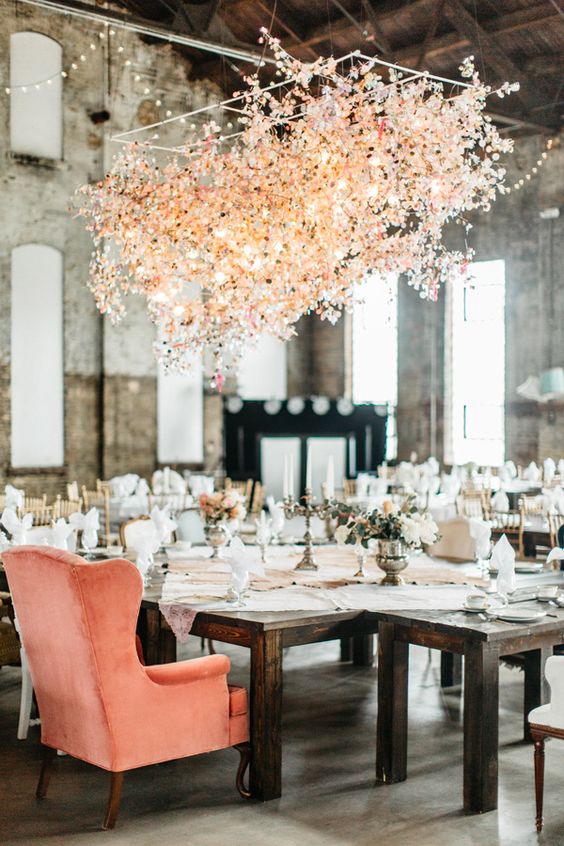 a beautiful overhead floral installation of blush and pink blooms and blooming branches over the table