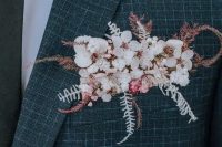 32 a grey and blue plaid print blazer styled with white and pink blooms, dried leaves and grasses that is a stylish and delicate accent