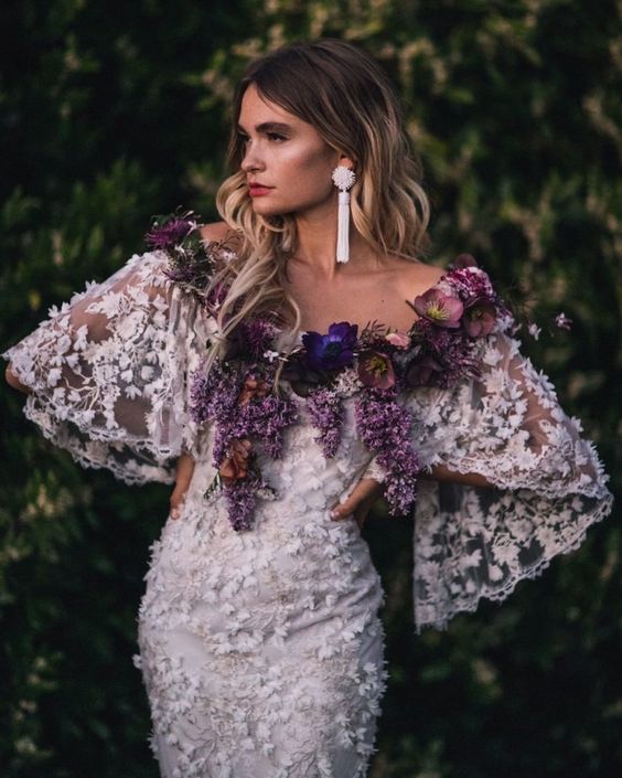 fresh flowers in purple and lilac covering the off the shoulder neckline for a touch of color and an unusual look