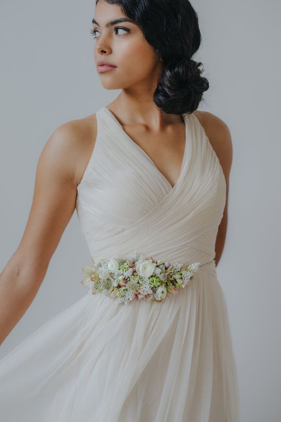 an elegant draped bridesmaid dress accessorized with a delicate neutral flower belt with greenery