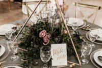 a 3D triangle with textural greenery and pink blooms and some floatign candles inside the centerpiece