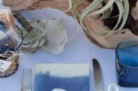 a beach wedding centerpiece of dirftwood, air plants, seashells and candles all around