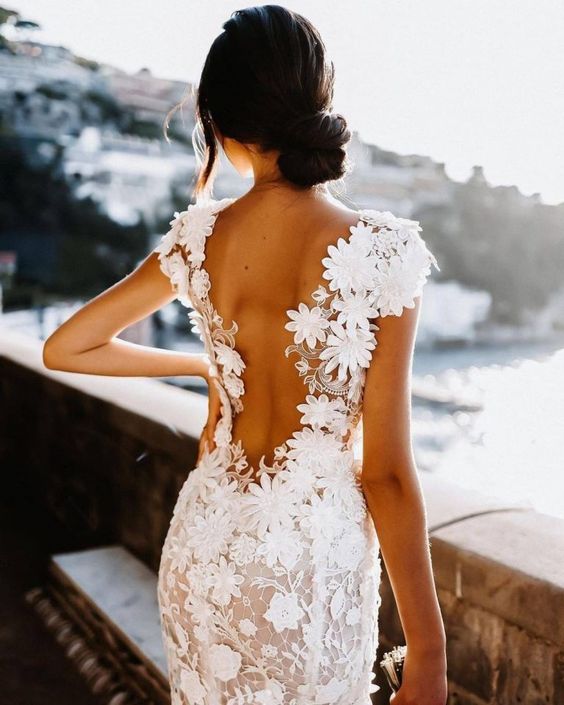 a beautiful blush fitting wedding dress covered with white lace floral appliques, with a cutout back and cap sleeves is amazing