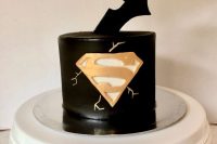 a black superhero groom’s cake that combines Superman and Batman signs and looks perfect