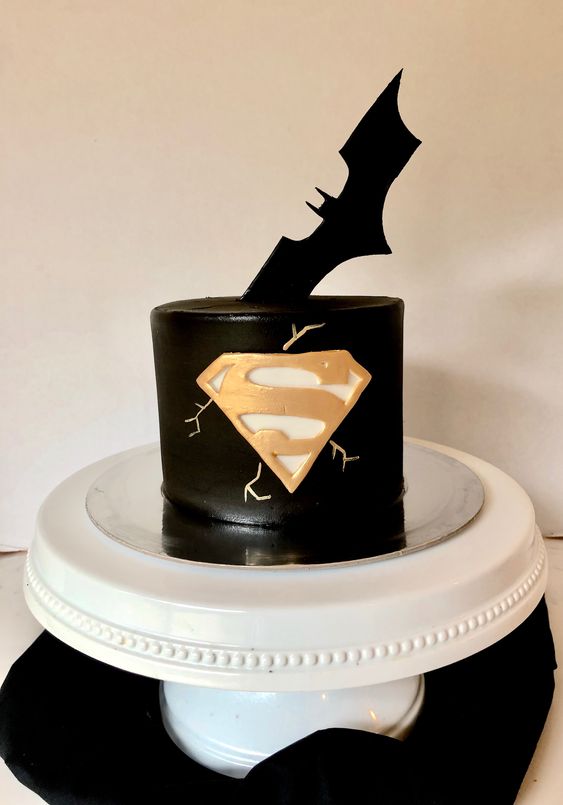 a black superhero groom's cake that combines Superman and Batman signs and looks perfect