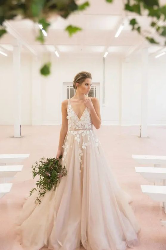a blush tulle wedding dress with white floral appliques on the bodice and partly on the skirt