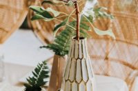 a boho desert wedding centerpiece with white vases, pots and greenery and a king protea