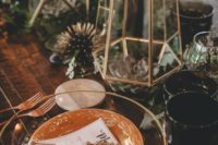 a boho tablescape with glass and porcelain plates, gilded terrariums with succulents and air plants, greenery and blooms