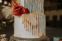 a bright boho wedding cake with catchy colorful detailing and feathers and bright blooms for a boho wedding