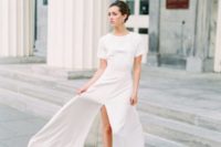 a casual plain maxi wedding dress with short sleeves, a high neckline, a front slit and blue heels plus statement earrings
