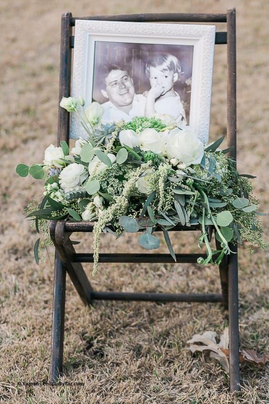 a chair with greenery and blooms and a photo of the deceased bride's father is a cool idea to honor him at the wedding