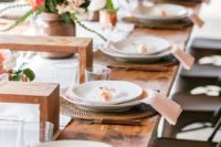 a chic and romantic spring bridal shower table with wicker chargers, wooden shelves, pastel blooms with greenery and cacti