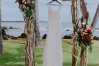 a chic driftwood wedding arch with greenery and bold blooms is amazing for a beach wedding