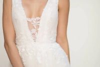 a chic floral applique wedding gown with a covered plunging neckline, no sleeves and an A-line skirt is a modern and edgy idea