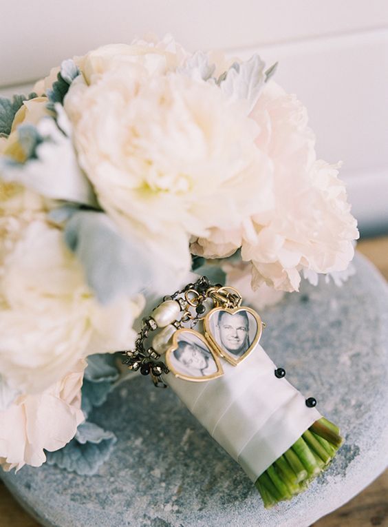 a classic white peony wedding bouquet with pale millet and photos of the loved deceased people is cool