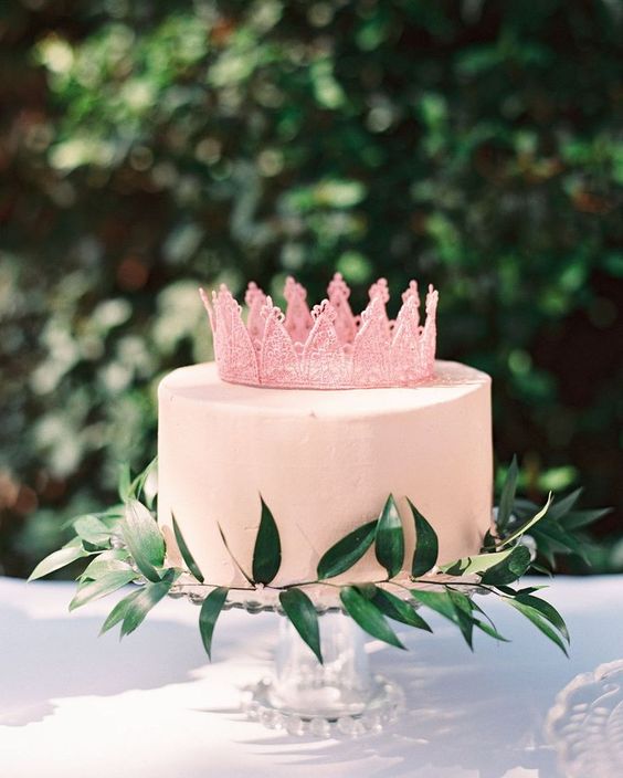 a cute pink bridal shower cake with a sugar crown and greenery is amazing for spring