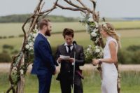 a driftwood wedding arch with greenery and white blooms is a gorgeous rustic idea