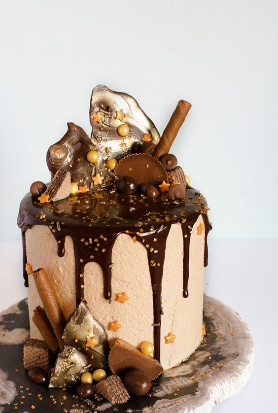 a drippy chocolate cake, with perfect drizzles of ganache, purposefully placed candy pieces and shards of chocolate looks absolutely delicious